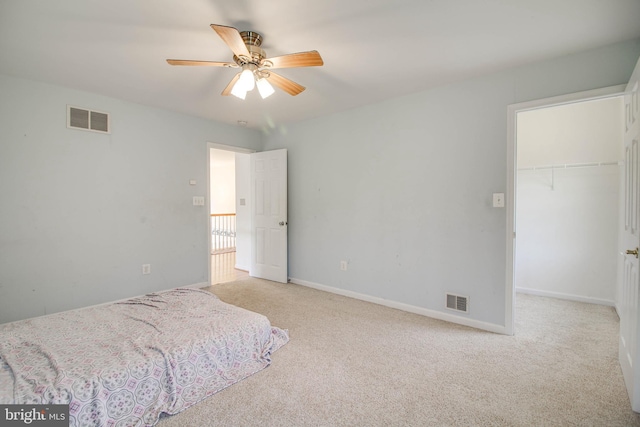 carpeted bedroom featuring a walk in closet, baseboards, a closet, and visible vents