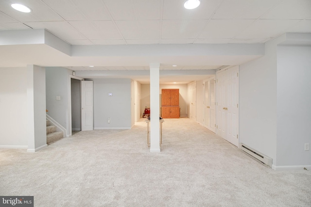 finished below grade area with light colored carpet, stairway, baseboards, a baseboard radiator, and a drop ceiling