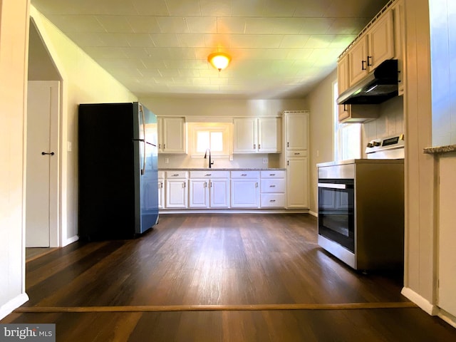 kitchen with dark wood-style floors, a sink, freestanding refrigerator, under cabinet range hood, and range
