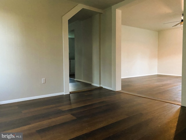 empty room featuring ceiling fan, baseboards, and wood finished floors