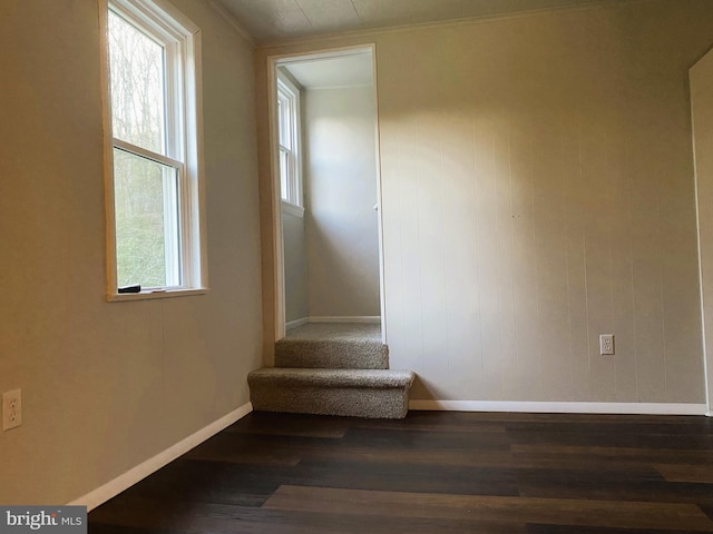 empty room with wood finished floors, baseboards, stairs, and ornamental molding