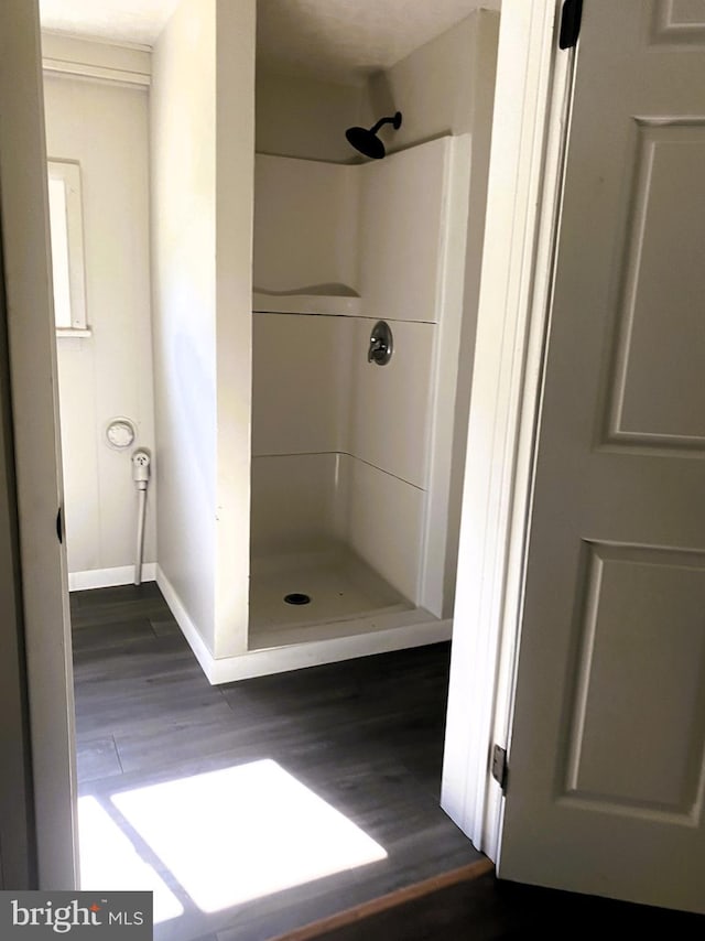 bathroom featuring a shower stall, wood finished floors, and baseboards