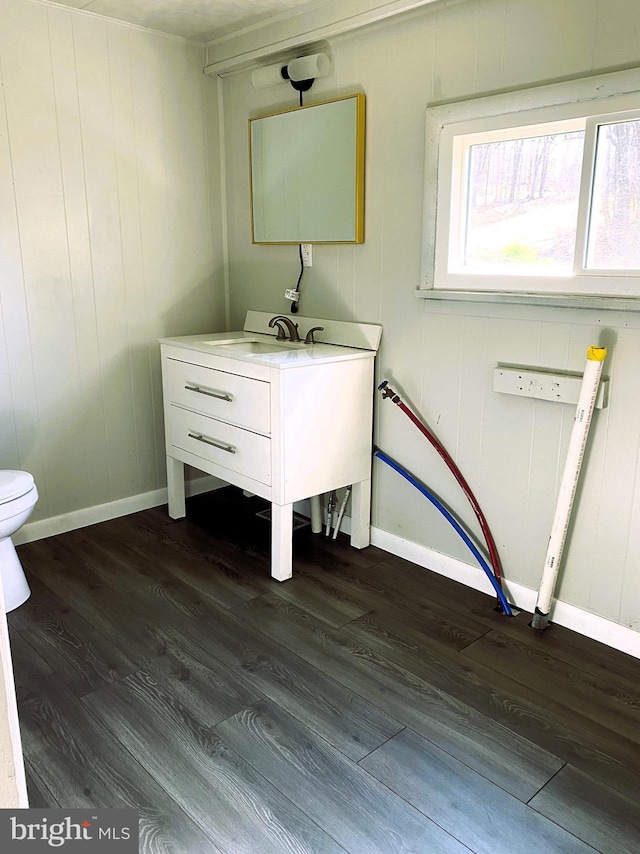 bathroom with wood finished floors, toilet, and baseboards