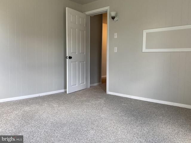 empty room featuring carpet and baseboards