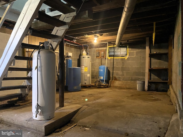 unfinished basement with stairs, electric water heater, and concrete block wall