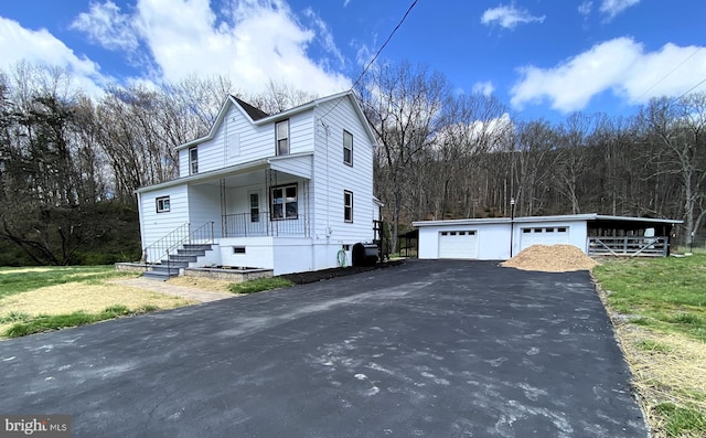 view of front of property with an outdoor structure, a detached garage, and covered porch