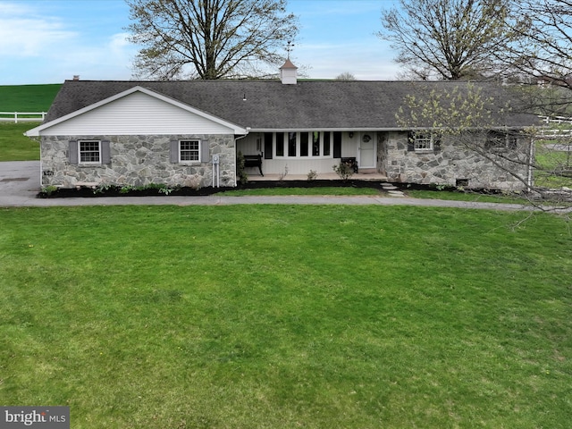 single story home featuring fence, stone siding, a shingled roof, and a front yard