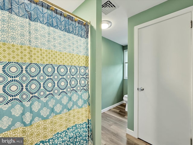 full bathroom featuring toilet, wood finished floors, curtained shower, baseboards, and visible vents