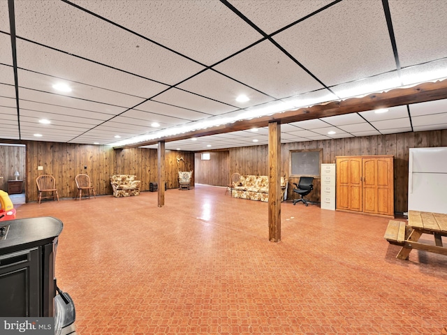 finished below grade area featuring tile patterned floors, wooden walls, recessed lighting, and a drop ceiling