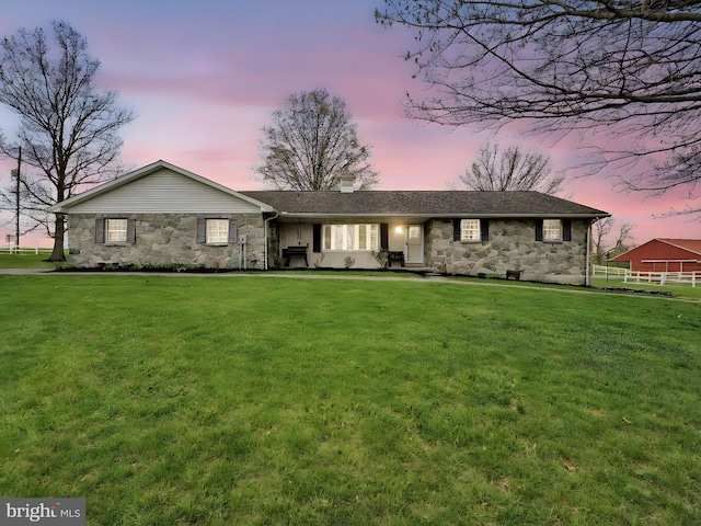 single story home with a yard, fence, and stone siding
