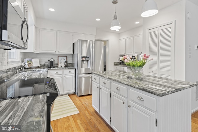 kitchen featuring a sink, white cabinets, stainless steel appliances, and light wood-style flooring