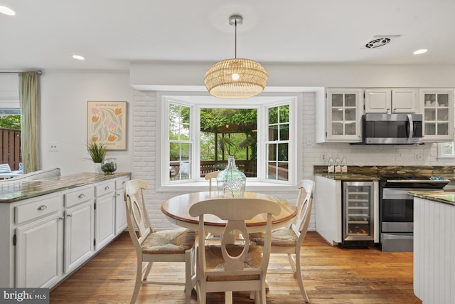 dining space featuring wine cooler, recessed lighting, wood finished floors, and visible vents