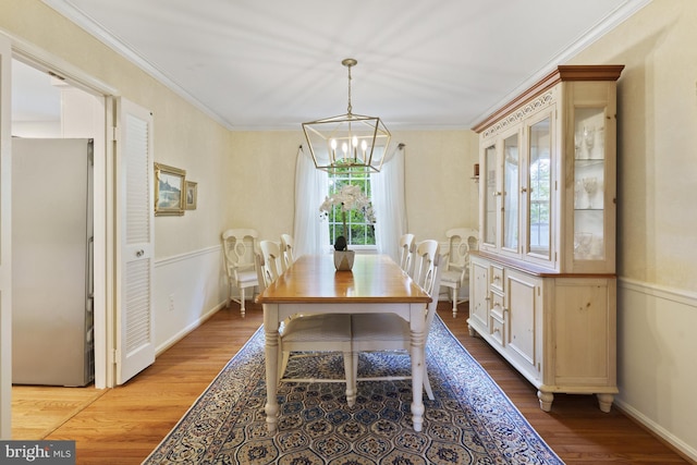 dining room featuring crown molding, wood finished floors, and a notable chandelier