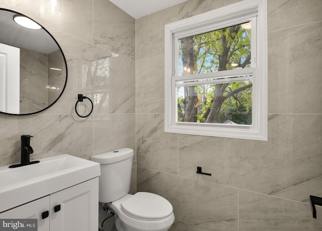 half bath featuring toilet, vanity, and tile walls