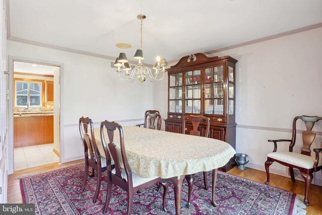 dining area featuring a chandelier, crown molding, and light wood finished floors