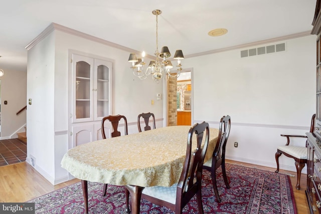 dining space featuring light wood-style flooring, a chandelier, stairway, and crown molding