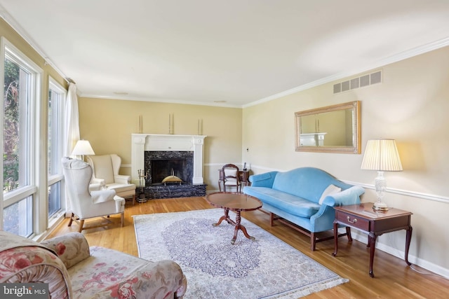 living area with wood finished floors, a premium fireplace, ornamental molding, and baseboards