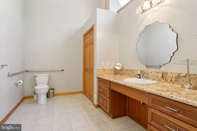 bathroom with vanity, toilet, baseboards, and tile patterned flooring