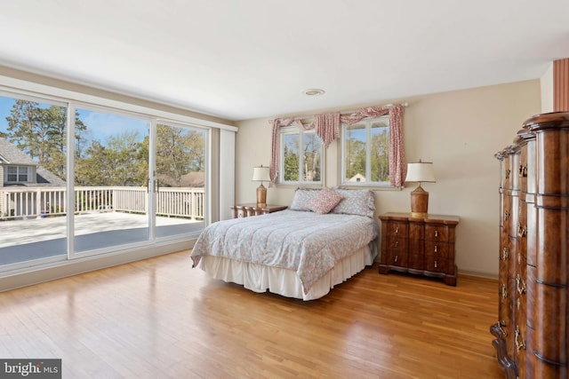 bedroom with access to exterior and wood finished floors