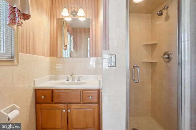 bathroom with a stall shower, vanity, and tile walls