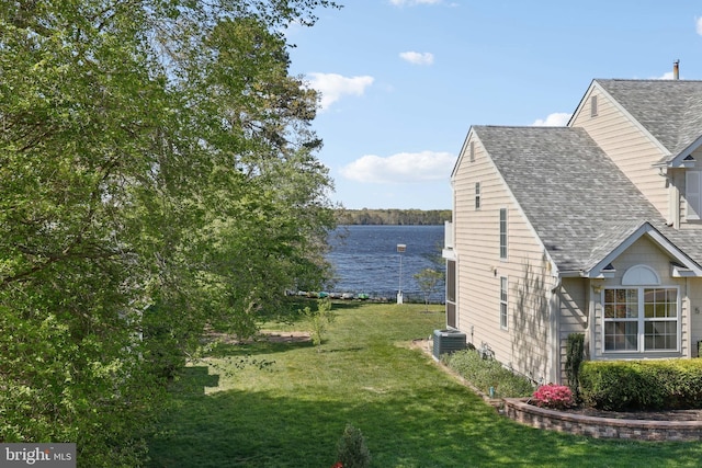 view of property exterior featuring roof with shingles, a yard, central AC, and a water view