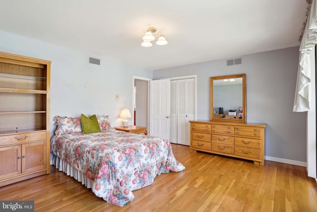 bedroom featuring a closet, light wood-type flooring, baseboards, and a chandelier