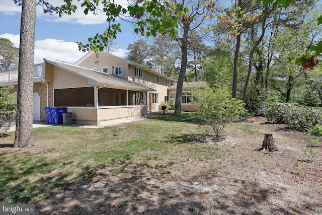 rear view of property featuring a sunroom, a lawn, and an attached garage