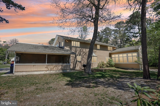 back of property with a sunroom and a lawn
