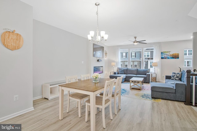 dining space with light wood-style floors, baseboards, plenty of natural light, and ceiling fan with notable chandelier