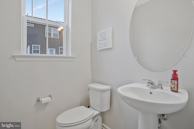 half bathroom featuring a sink, baseboards, and toilet