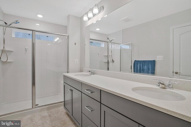 bathroom featuring double vanity, tile patterned floors, a shower stall, and a sink