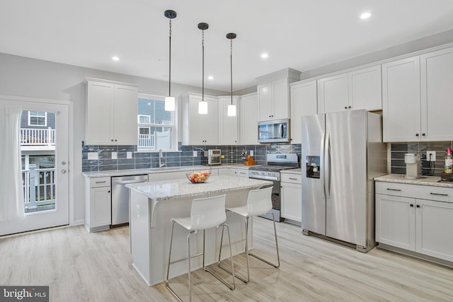 kitchen featuring a kitchen island, stainless steel appliances, decorative backsplash, and light wood finished floors