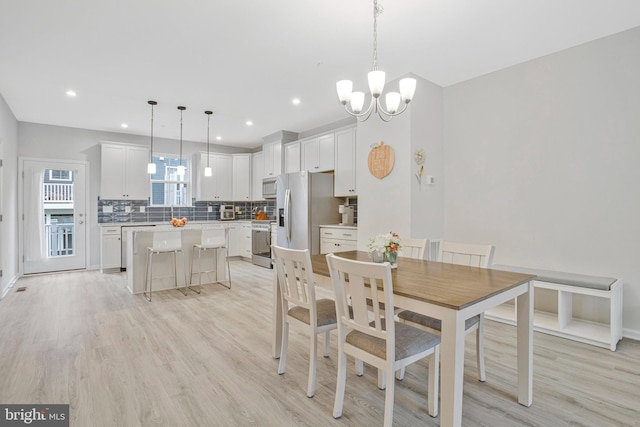 dining space with recessed lighting, baseboards, an inviting chandelier, and light wood-style flooring