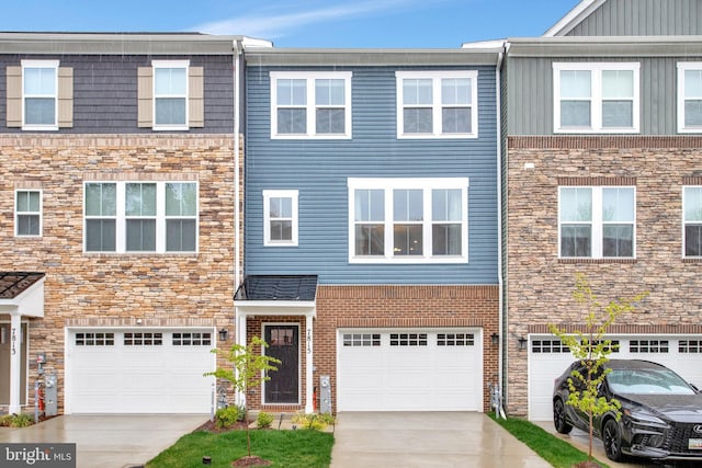 townhome / multi-family property with an attached garage, driveway, and stone siding