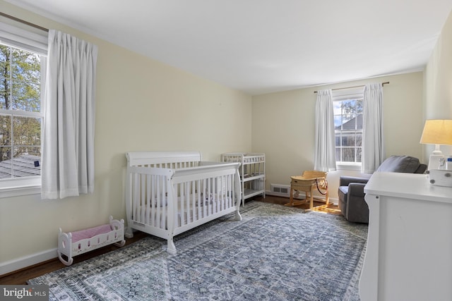 707 Greenwood Rd, Wilmington, DE 19807 - bedroom with a crib, baseboards, wood finished floors, and multiple windows