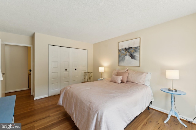 bedroom featuring a textured ceiling, baseboards, wood finished floors, and a closet