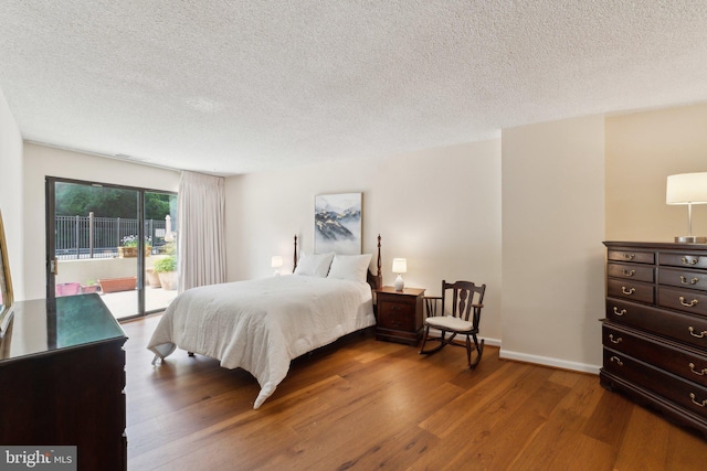 bedroom featuring baseboards, a textured ceiling, access to exterior, and wood finished floors