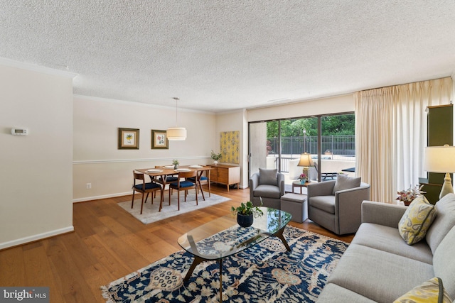 living area featuring baseboards, ornamental molding, a textured ceiling, and wood finished floors
