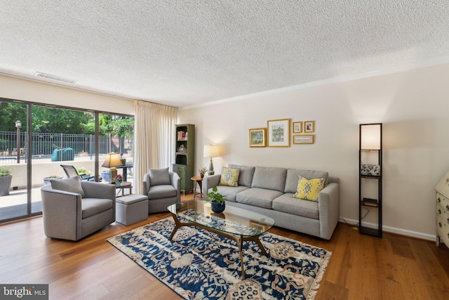living area featuring wood finished floors, a textured ceiling, and visible vents