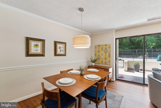 dining room featuring crown molding, a textured ceiling, visible vents, and wood finished floors