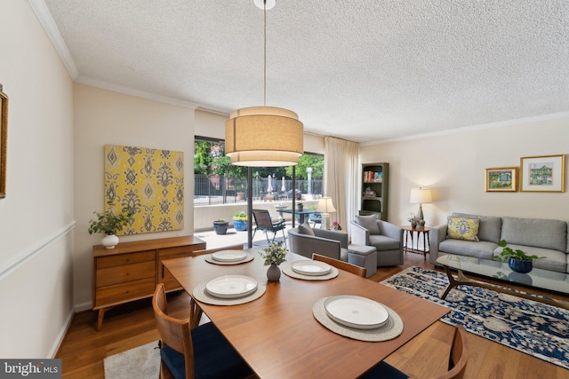 dining room with crown molding, a textured ceiling, and wood finished floors