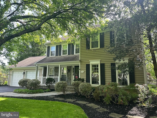 view of front of home with a garage, a front lawn, covered porch, and driveway