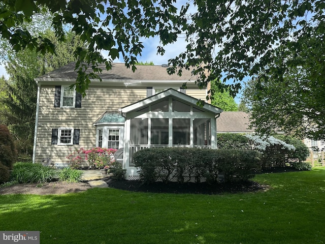rear view of property with a lawn and a sunroom