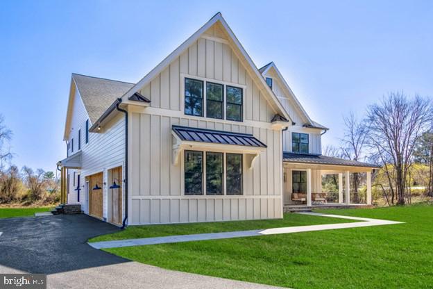13 Sugarvale Way, Lutherville Timonium, MD 21093 - back of house with board and batten siding, an attached garage, a standing seam roof, driveway, and a lawn