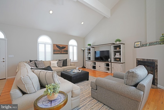 living area featuring beam ceiling, high vaulted ceiling, light wood finished floors, a fireplace, and recessed lighting