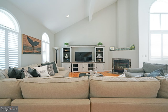 living room with wood finished floors, high vaulted ceiling, and a fireplace with flush hearth