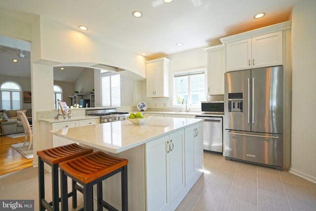 kitchen with appliances with stainless steel finishes, plenty of natural light, a kitchen island, white cabinets, and recessed lighting