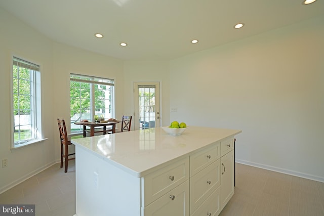 kitchen featuring recessed lighting, healthy amount of natural light, white cabinetry, a kitchen island, and baseboards