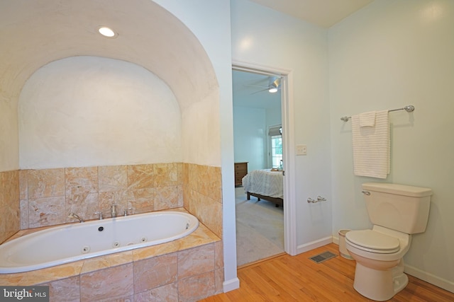 full bathroom with wood finished floors, ensuite bathroom, a whirlpool tub, toilet, and a ceiling fan