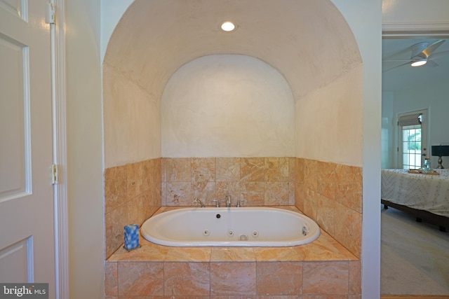 ensuite bathroom with a tub with jets and a ceiling fan